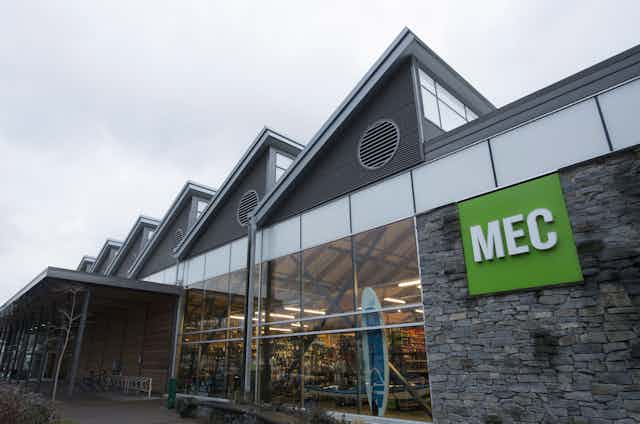 The green MEC sign is seen outside a gray stone and glass building.