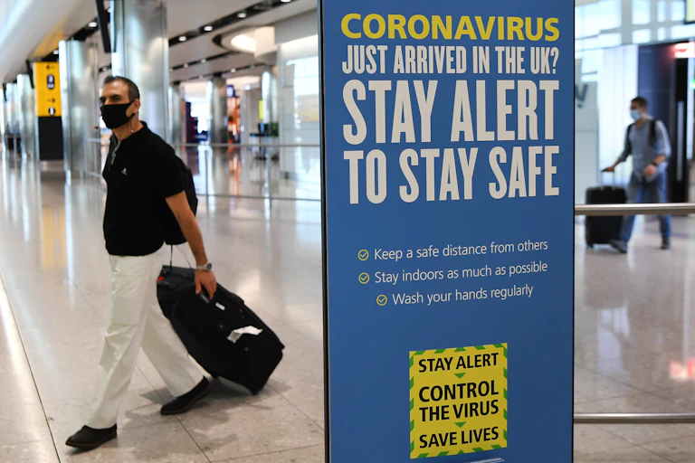 A UK government COVID-19 information poster at an airport.