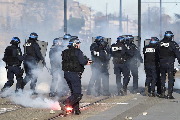 French riot policemen advance during clashes with protesters
