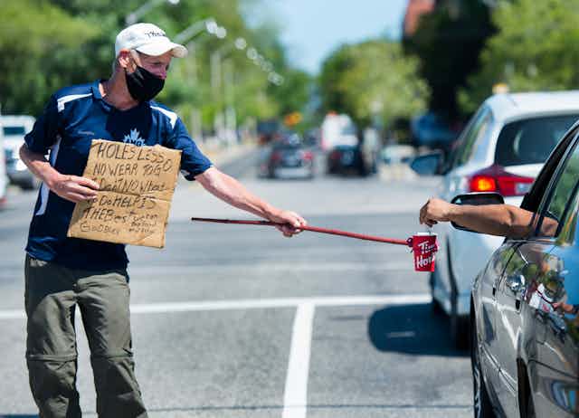 A homeless man uses a self-made contraption to properly physical distance while panhandling for money during the COVID-19 pandemic in Toronto.