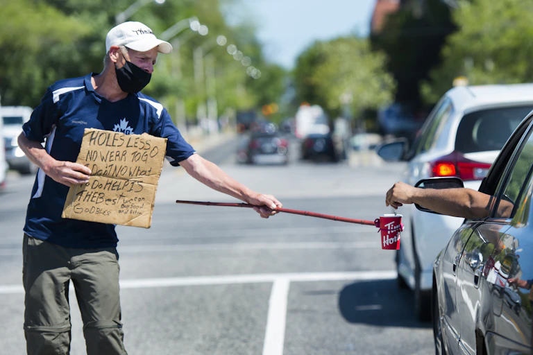 A homeless man uses a self-made contraption to properly physical distance while panhandling for money during the COVID-19 pandemic in Toronto.