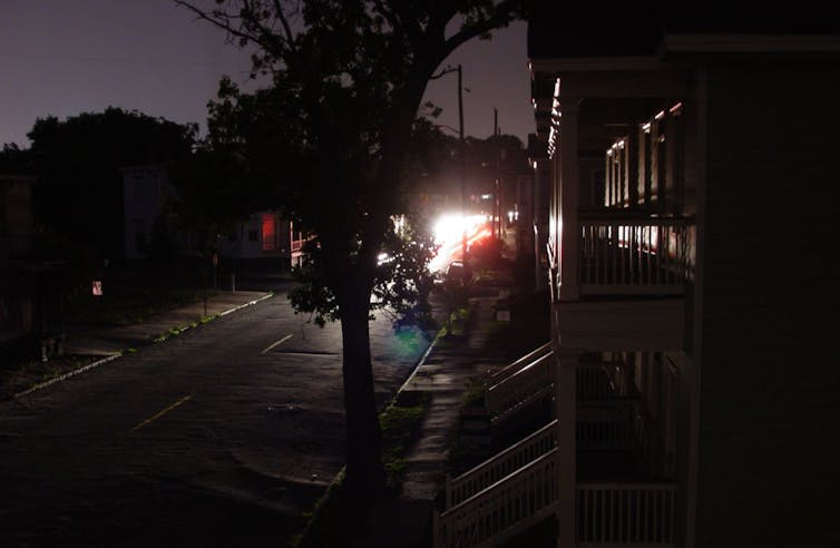 A darkened street with car lights in the distance