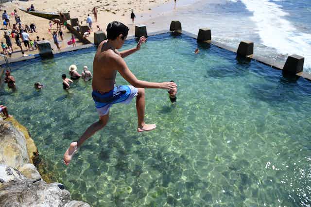 A boy jumps into an ocean pool in Sydney.