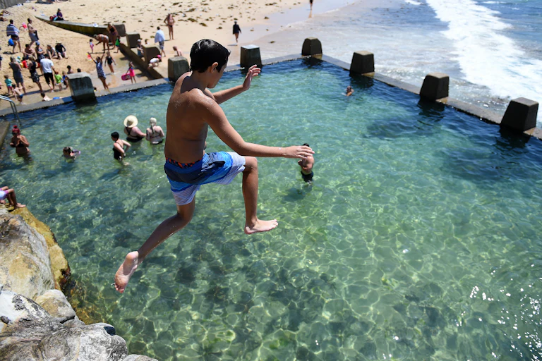 A boy jumps into an ocean pool in Sydney.