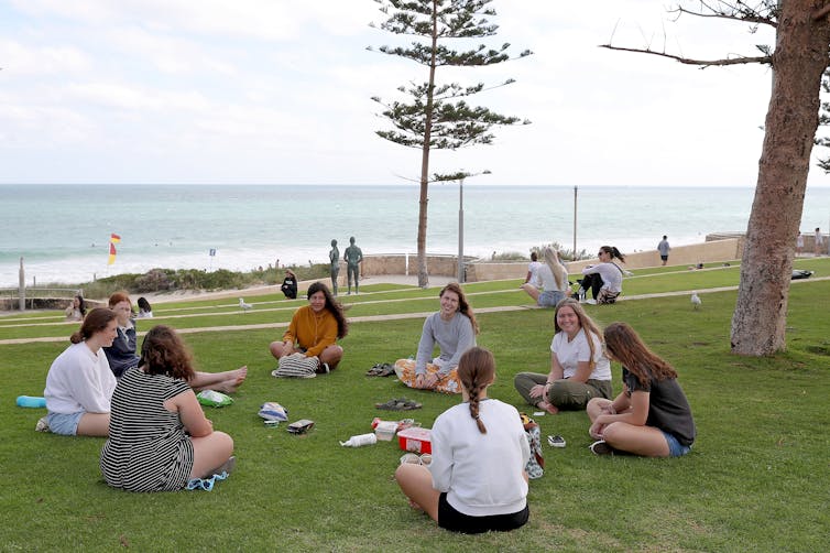People maintain social distance while at a beach picnic.