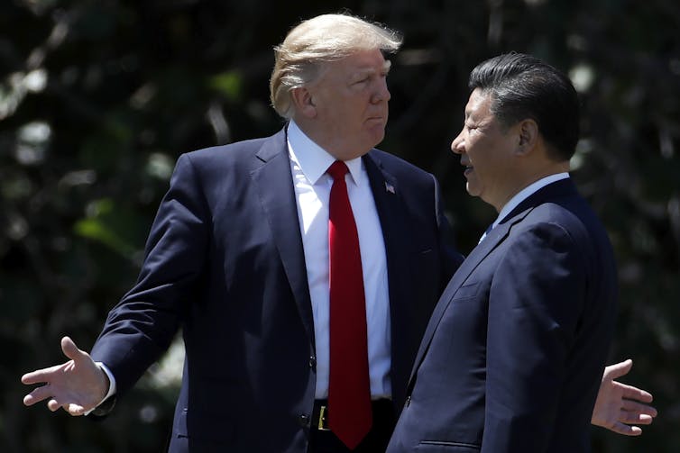 Donald Trump talks to Xi Jinping with arms outstretched