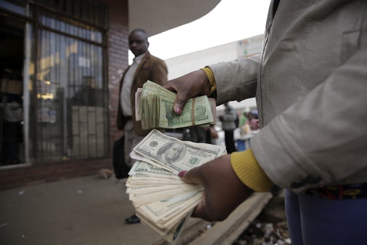 A foreign currency trader holds Zimbabwe US dollars in Harare, Zimbabwe,