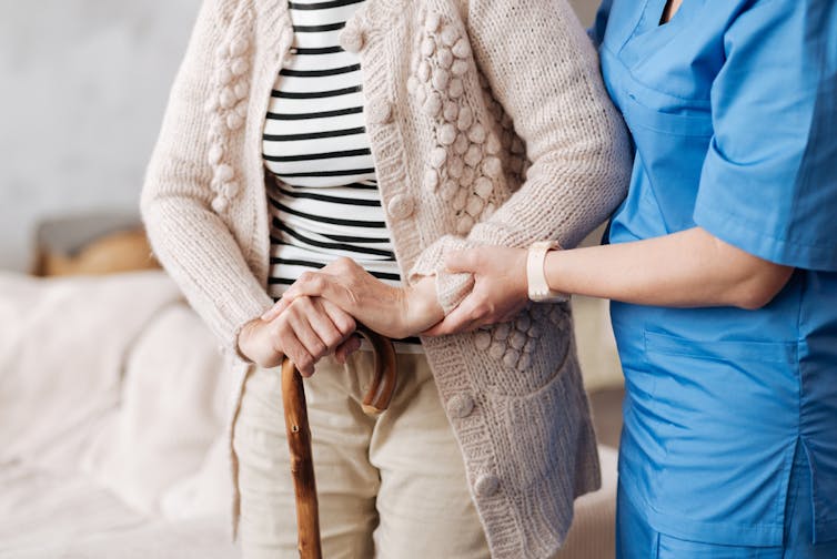 An elderly person in their home being helped by a nurse