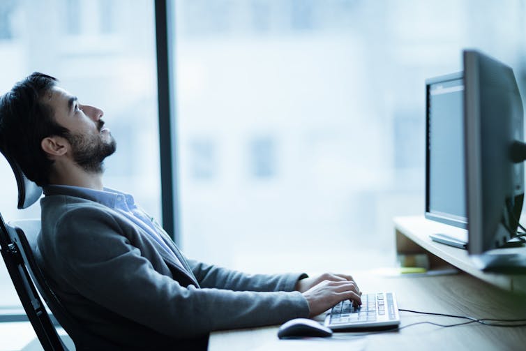 Stressed man leaning back from computer