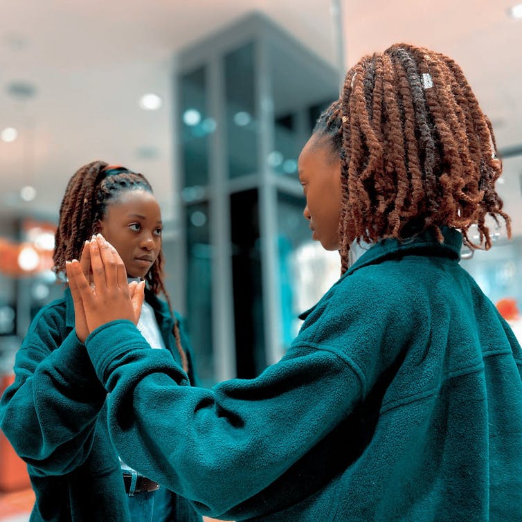 Girl in denim jacket looking in the mirror.