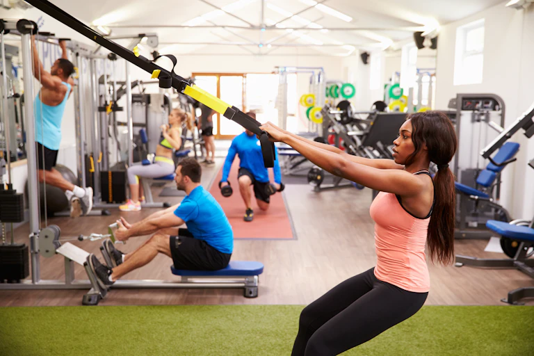 Woman uses gym equipment for perform a pull-up.