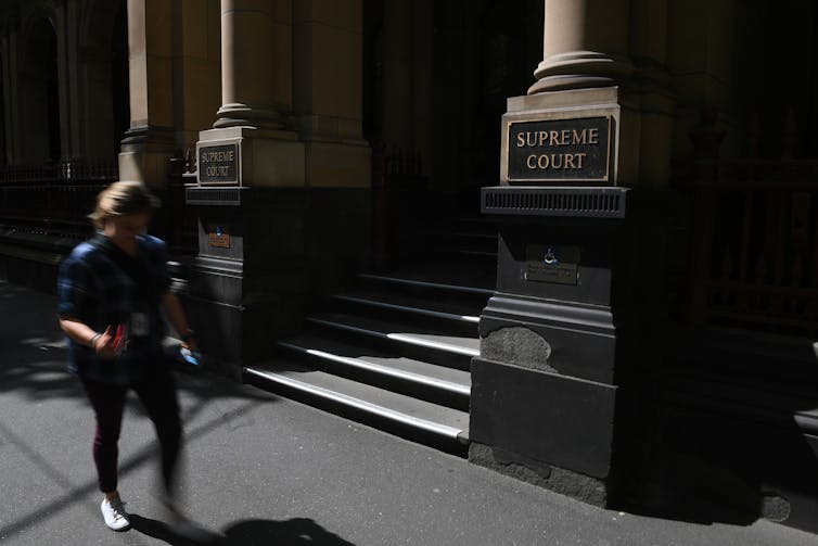 Woman walking past Supreme Court Melbourne.