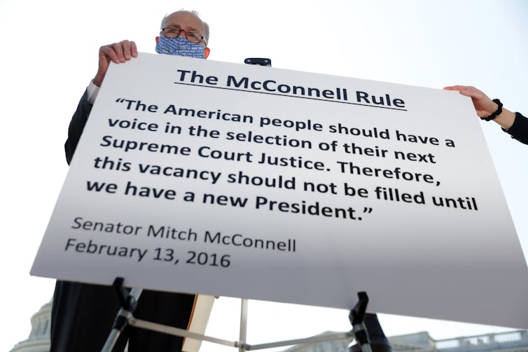 Schumer holds a sign reading, 'The American people should have a voice in the selection of their next Supreme Court Justice. Therefore, this vacancy should not be filled until we have a new President.'