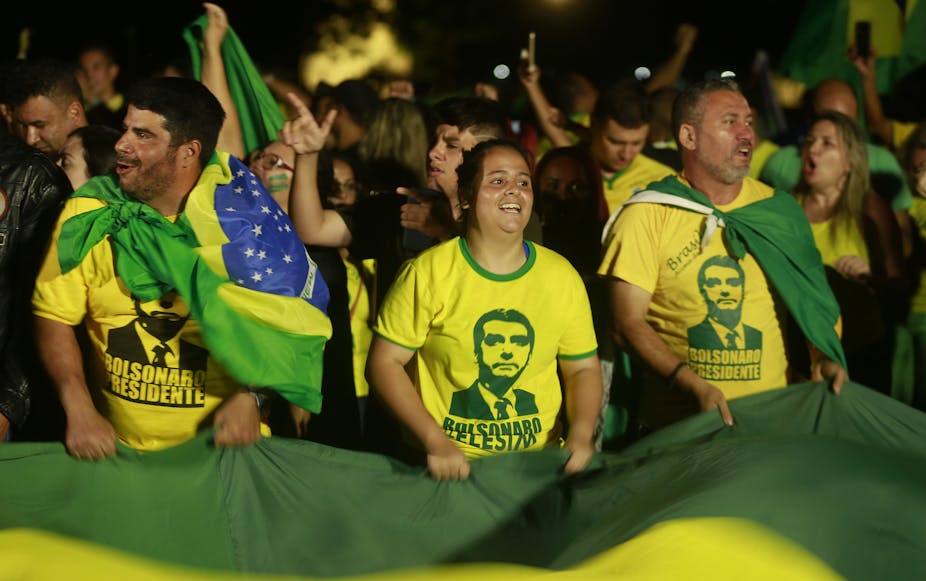 Crowd wearing T-shirts with Jair Bolsonaro's face on.