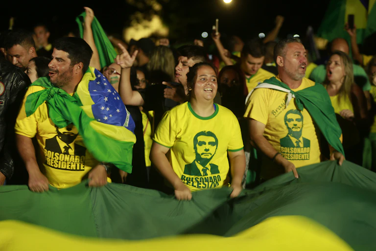 Crowd wearing T-shirts with Jair Bolsonaro's face on.