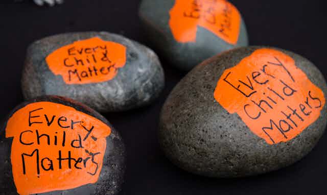 Rocks painted to say 'every child matters.'