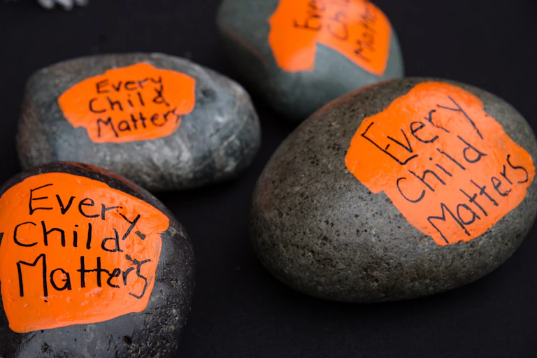 Rocks painted to say 'every child matters.'