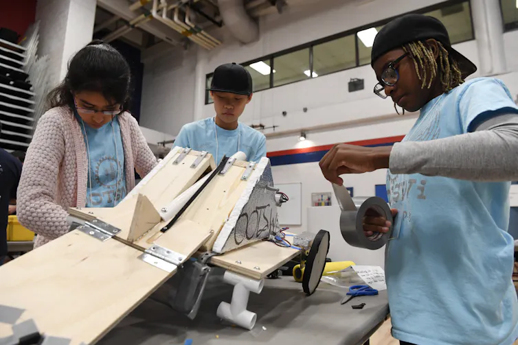 three tweens work together in a robotics competition