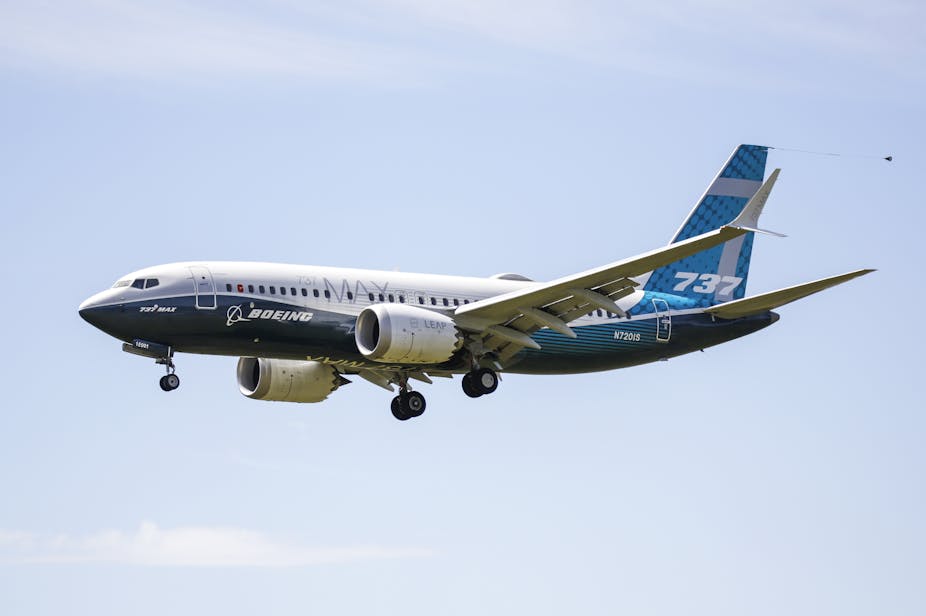A Boeing 737 Max flying with its landing gear coming down.
