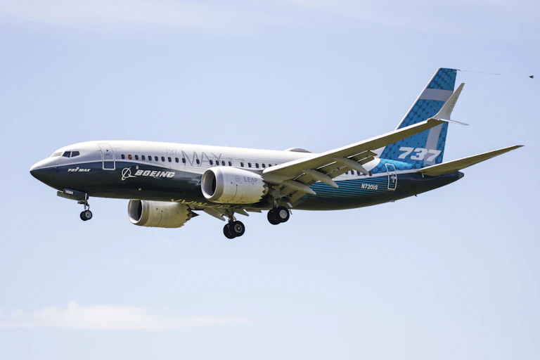 A Boeing 737 Max flying with its landing gear coming down.