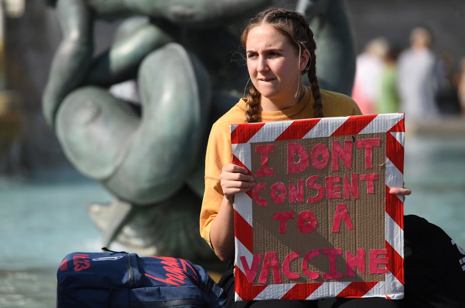 A person holding a sign that says I don't consent to a vaccine
