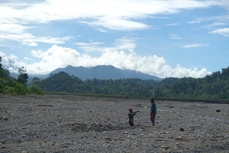 Two people, one waist-deep in tailings.