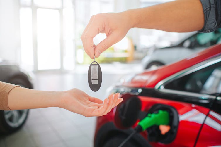 Hands transferring keys to an electric car.