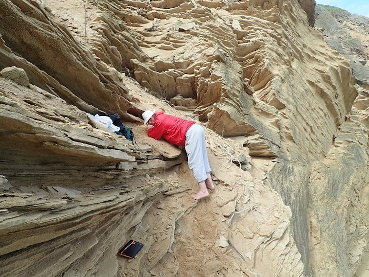 A man steadies himself on a cliff.