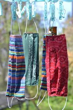 Four cloth masks hanging on a clothesline.