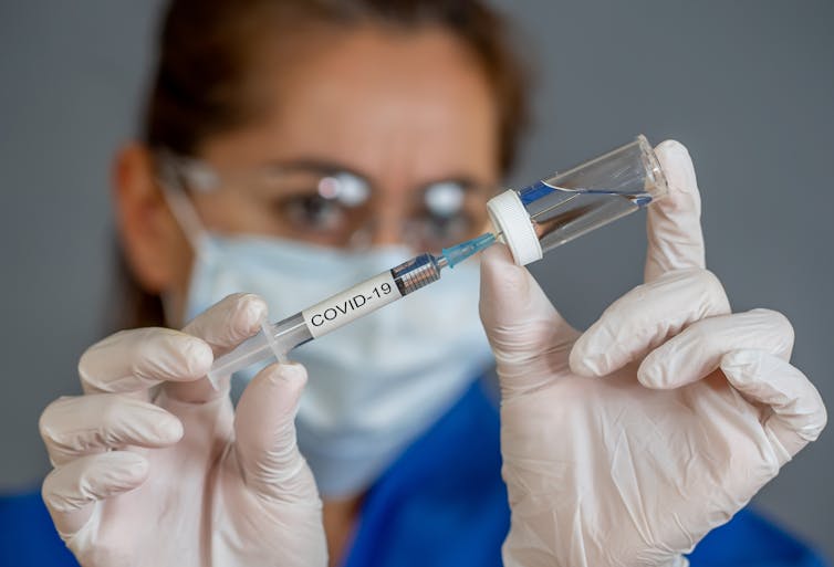 Picture of a woman holding a coronavirus vaccine and needle.