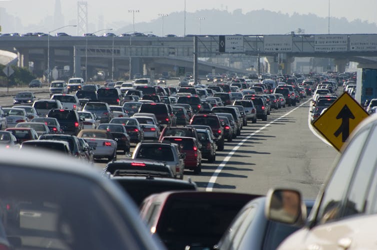 A traffic jam of cars with a bridge running over
the road in the distance.