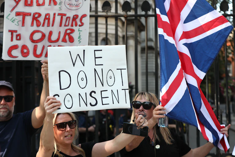 A woman holding a sign reading 'we do not consent'.
