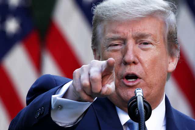 President Donald Trump points toward the camera in a press briefing.