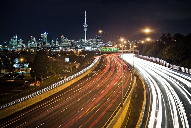 Vehicle lights blur at night on a busy motorway into Auckland.