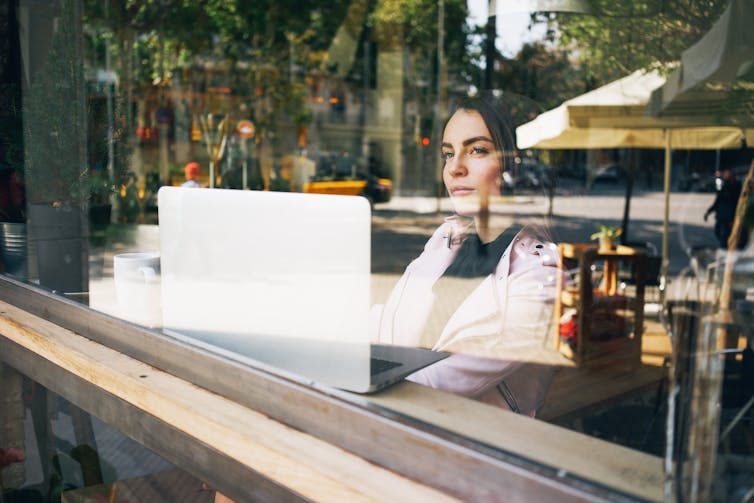 Woman sits in cafe with laptop