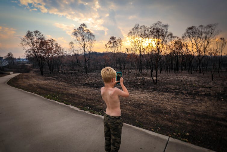 Boy takes photo of burned landscape