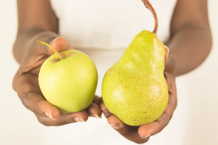 Person holding an apple and a pear.