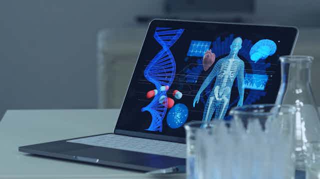 Probets ante un ordenador en el que se ven pastillas, un genoma y un cuerpo humano.