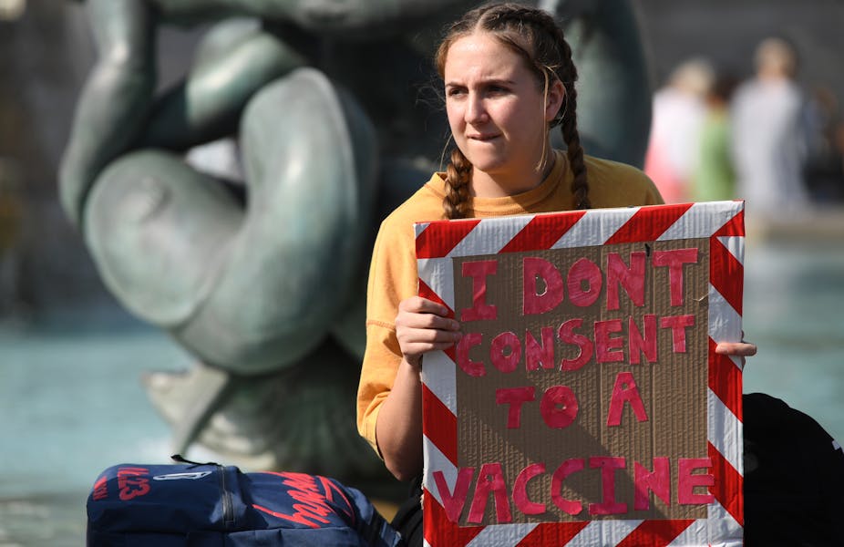 A girl holding a sign saying: 'I don't consent to a vaccine'