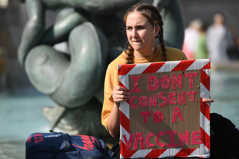 A girl holding a sign saying: 'I don't consent to a vaccine'