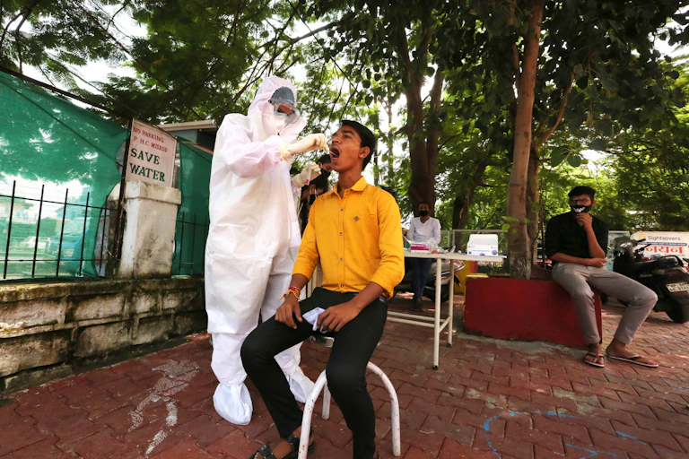 Man sits while medical worker takes coronavirus swab test.