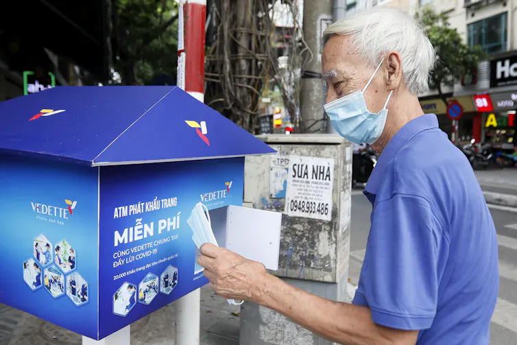 A man taking a disposable mask from a box in Hanoi, Vietnam