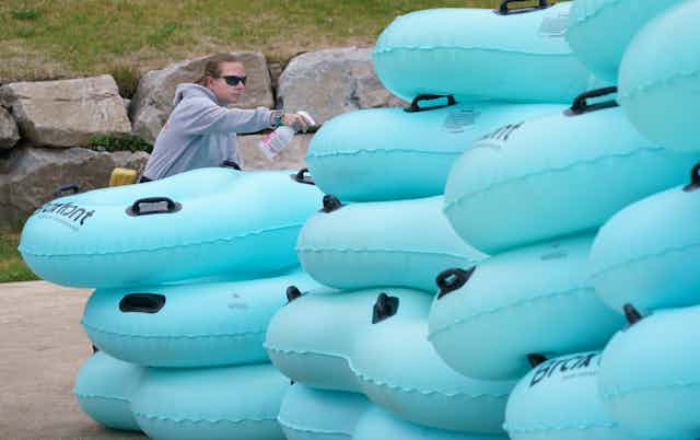 A lifeguard sprays disinfectant on inflatable rafts.