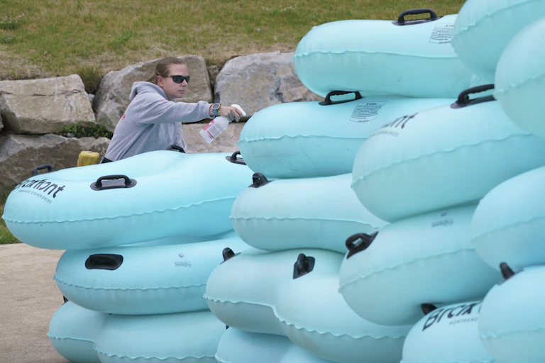 A lifeguard sprays disinfectant on inflatable rafts.