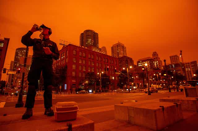 A worker in San Francisco eats lunch under a sky turned orange by wildfire smoke.