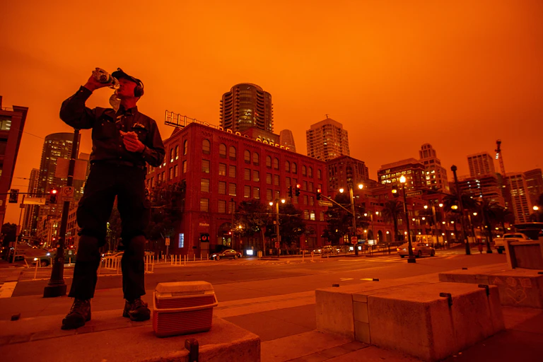 A worker in San Francisco eats lunch under a sky turned orange by wildfire smoke.