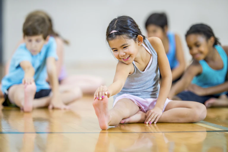 Several children on the floor, stretching.
