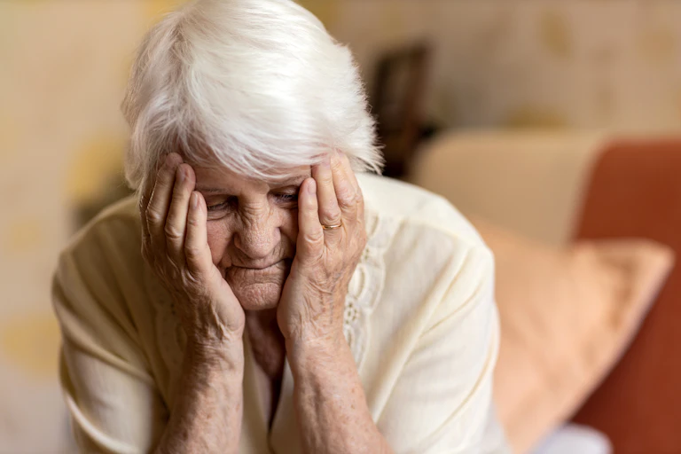 An old woman holds her head in her hands.