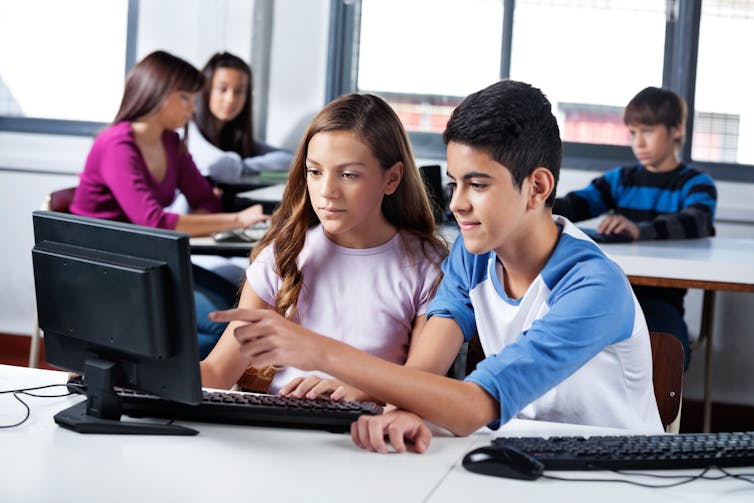 Teenage girl and boy looking at computer screen.