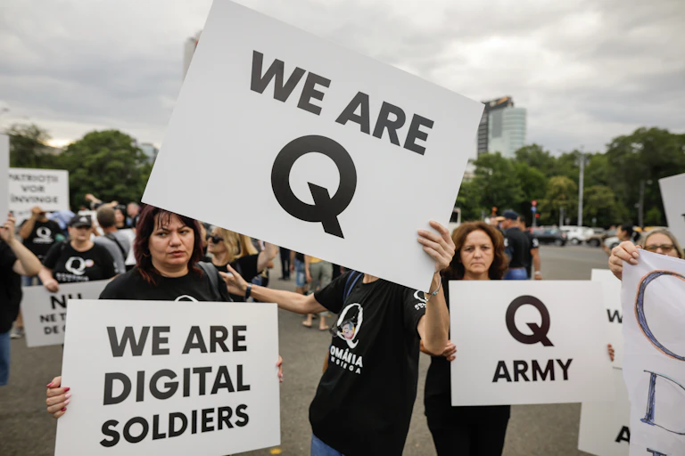 People display Qanon messages on cardboard signs at a political rally.